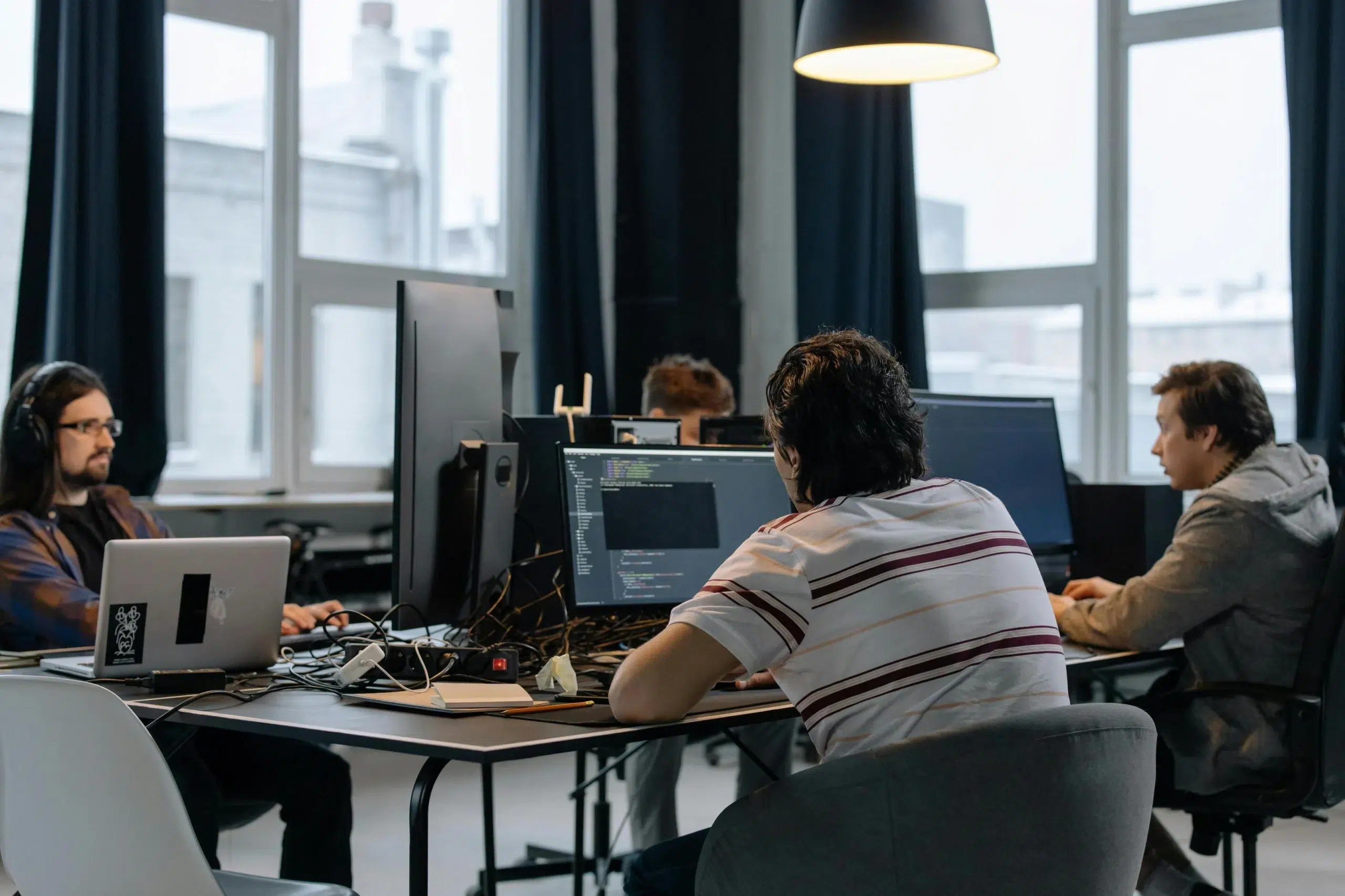 Software engineers and project admins sitting at workstations running diagnostics and testing workflows on desktop computers before system go-live.