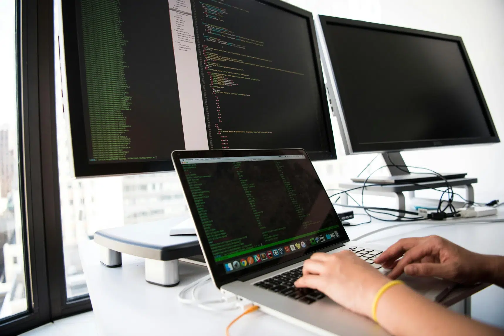 Developer working on multiple monitors with code displayed on screens