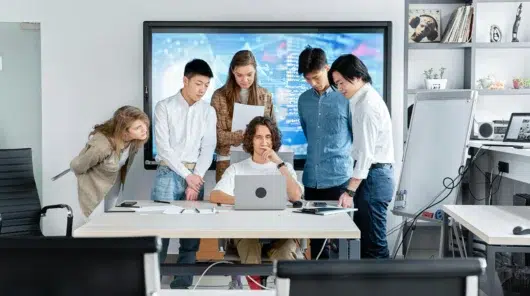 Cross-functional team gathered around a laptop evaluating CMMS software implementation options