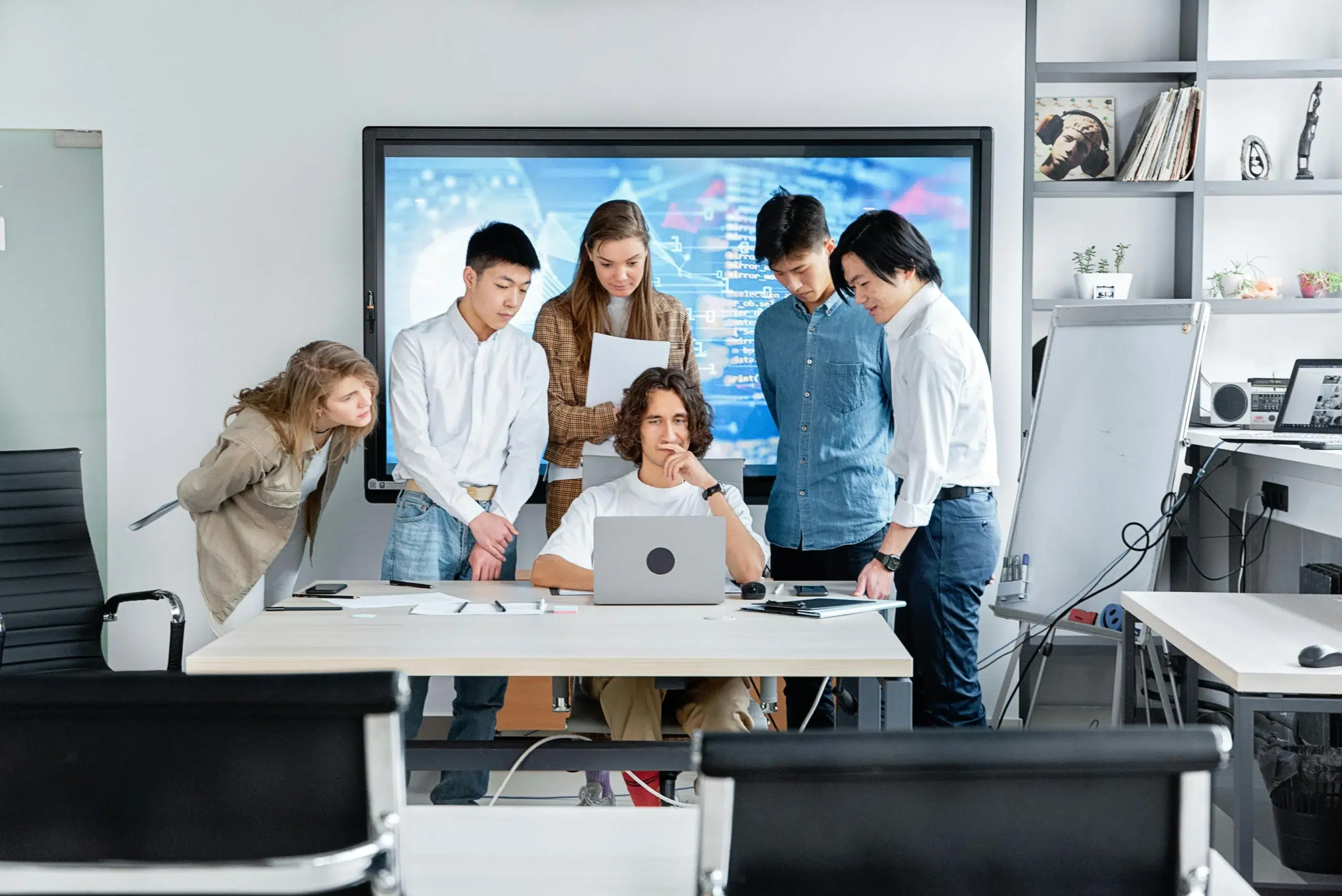 Cross-functional team gathered around a laptop evaluating CMMS software implementation options