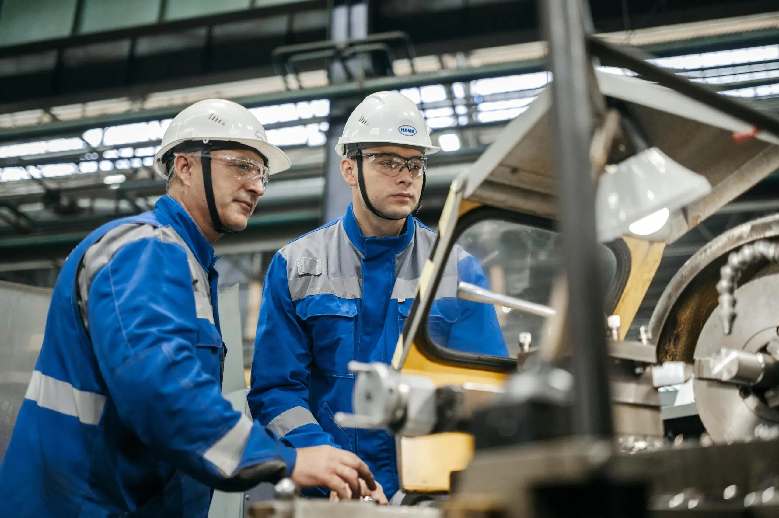 Two manufacturing workers in hard hats reviewing machinery during a preventive maintenance check